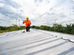 Commercial roofing contractor inspecting a damaged flat roof with visible cracks, ponding water, and leak warning signs on a commercial building.