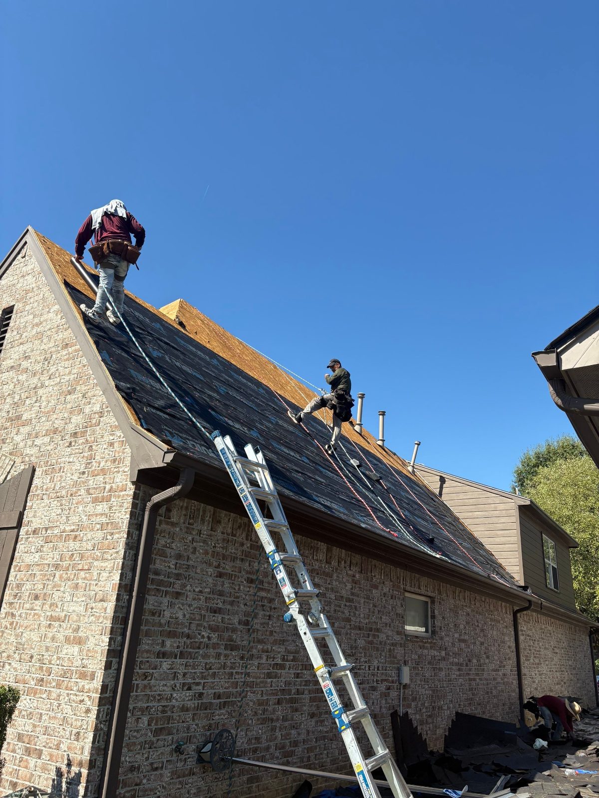 Roofers tied off on a steep roof in Lakeland TN